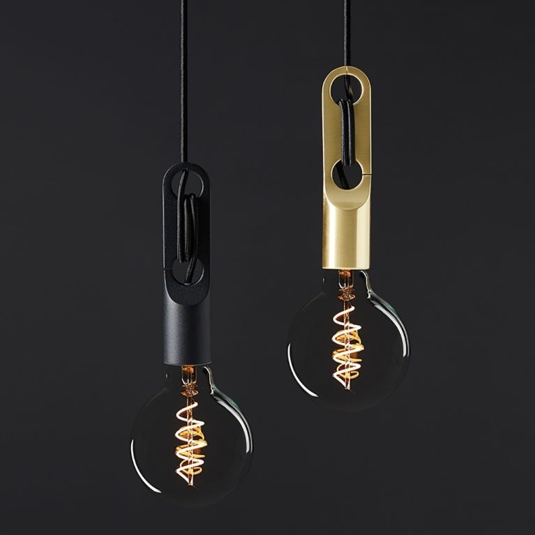 Two Loop Pendant lights with exposed filament bulbs, one with a black holder and the other with a brass holder, hanging against a dark background.