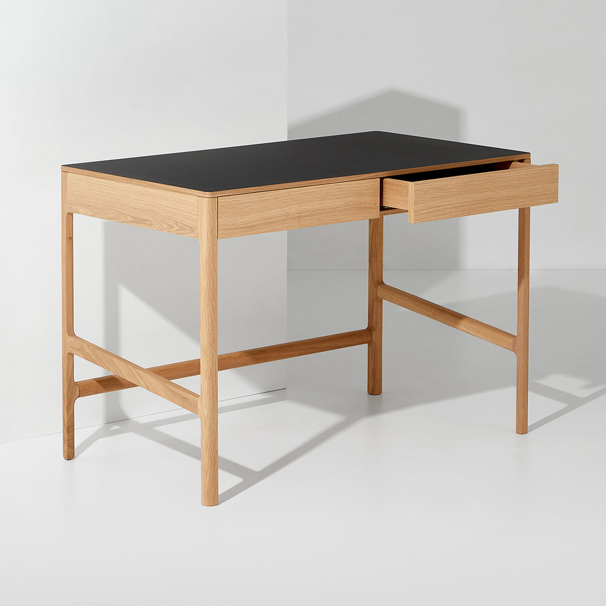 A Dormus wooden desk with a black top and a single open drawer, set against a white background, highlighting its clean lines and functional design.