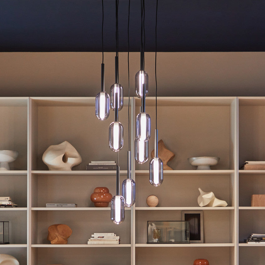 Droplet Dimmable Nine Cluster Ceiling lights with elongated glass bulbs hanging in front of a set of shelves displaying various decorative objects.